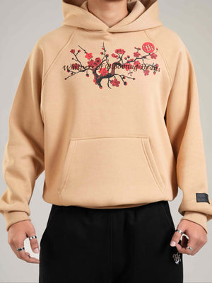 Beige hoodie with cherry blossom design worn by a person on a gray background