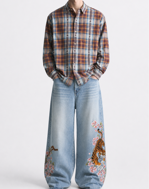 Person wearing a plaid shirt and jeans with tiger designs on a white background