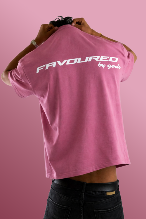 Person wearing a pink t-shirt with 'FAVOURED by gods' text on the back against a pink background
