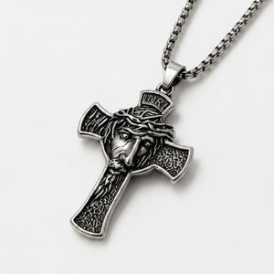 Silver cross pendant with Jesus face design on a white background
