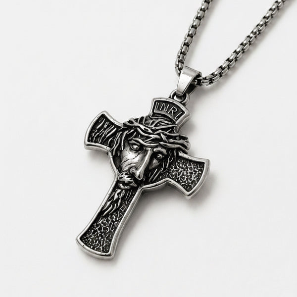 Silver cross pendant with Jesus face design on a white background